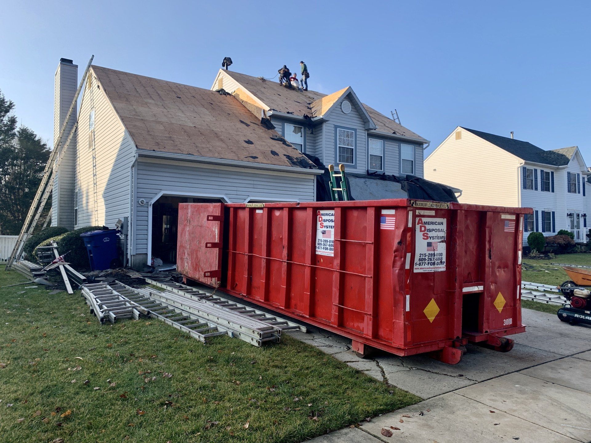 A thirty cubic yard dumpster truck is parked in front of a house