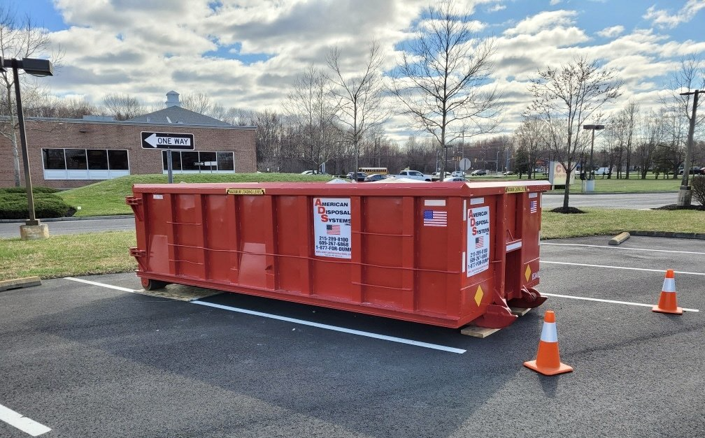 A fifteen cubic yard red dumpster is parked in a parking lot.