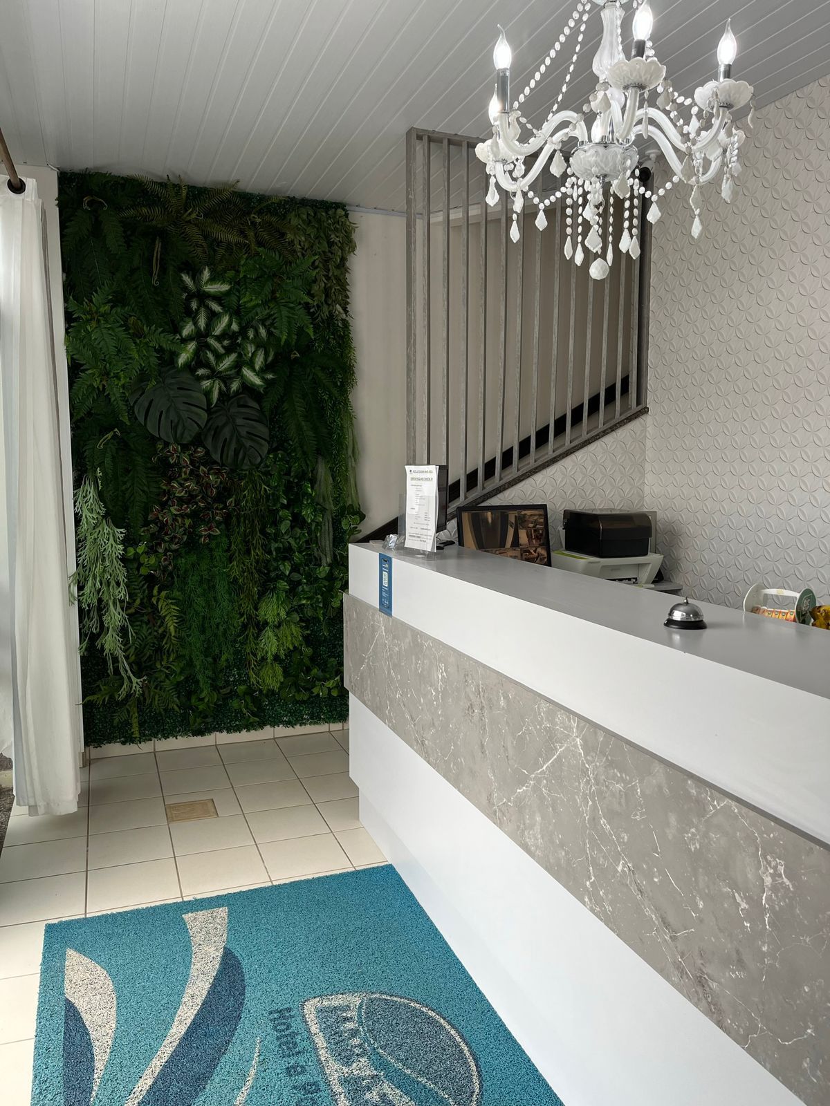 Uma área de recepção com um lustre e uma parede verde.