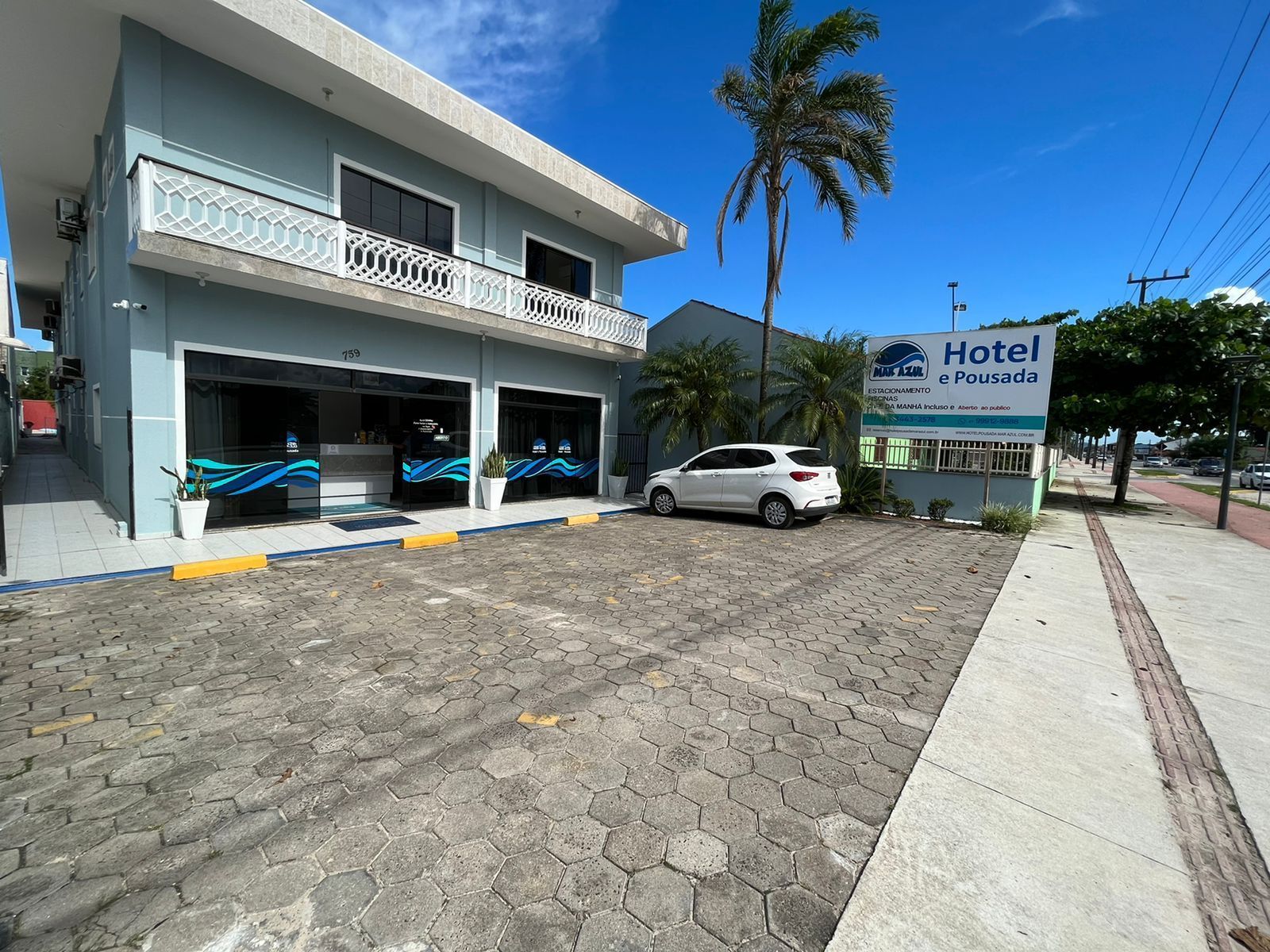 Um carro branco está estacionado em frente a um hotel.
