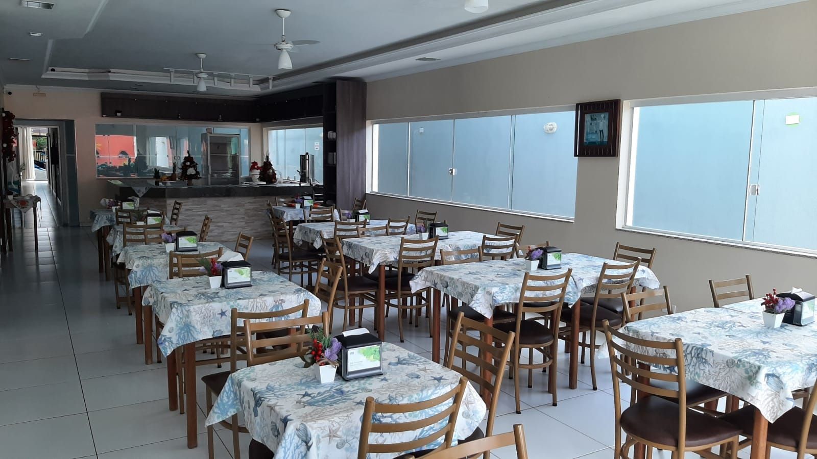 Um restaurante com mesas e cadeiras e uma televisão na parede.