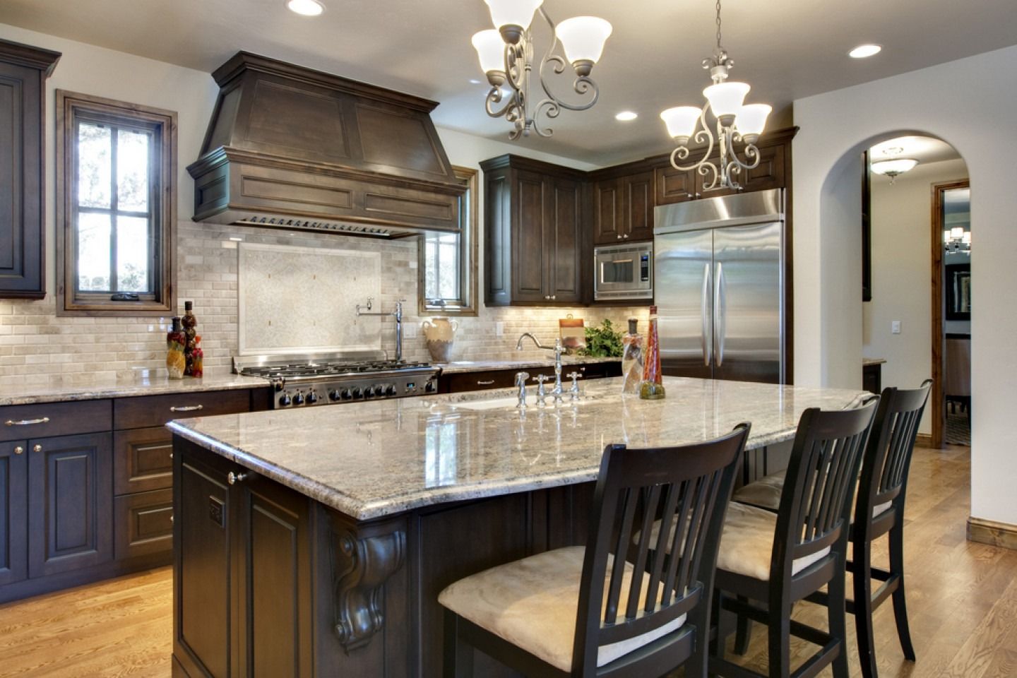 Modern kitchen with dark cabinets, large island, stainless appliances, and pendant lights