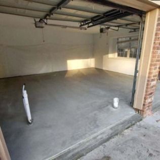 Empty unfinished garage with bare concrete floor and exposed ceiling beams