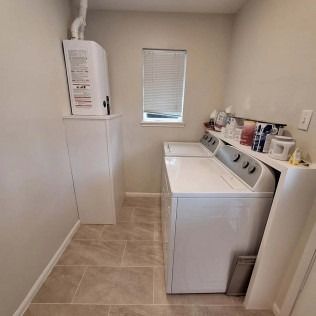 Laundry room with washer and dryer, white walls, beige tile floor, and a small window.