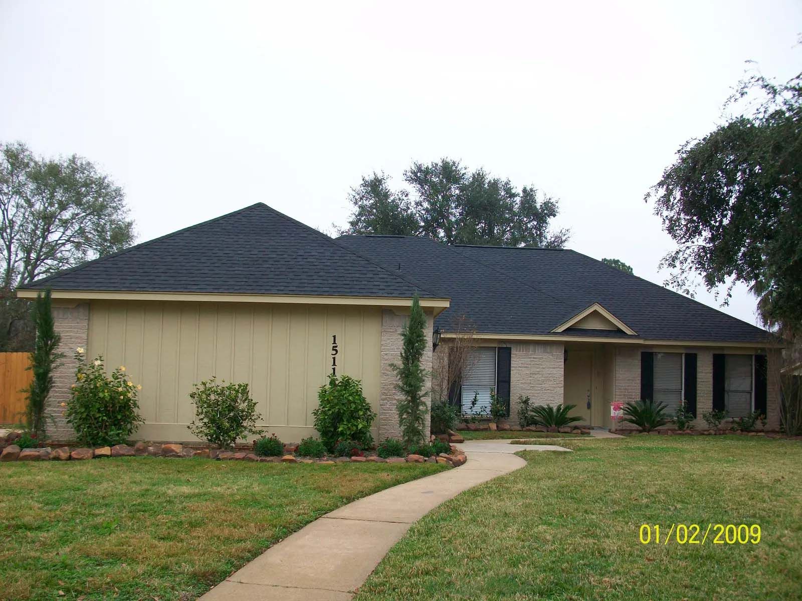Single-story suburban house with dark roof, beige walls, and curved walkway in front.