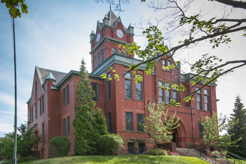 Red brick courthouse building with clock tower, blue sky.