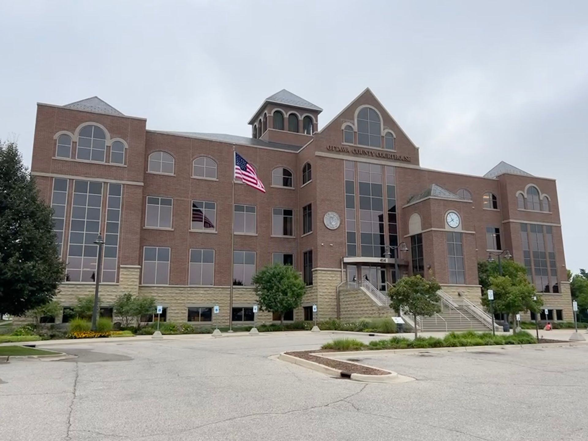 Brick building, Cass County Courthouse, with US flag and cloudy sky.