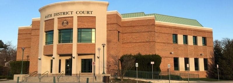A courthouse building with brick exterior and arched entrance, under a clear sky. The building says 