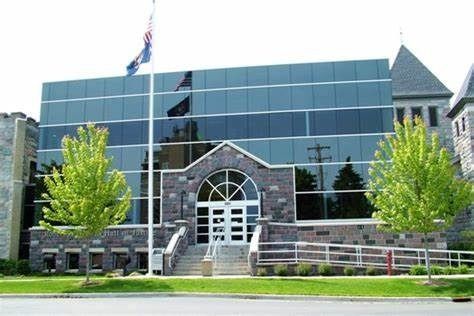 Modern glass building with stone facade and American flag.