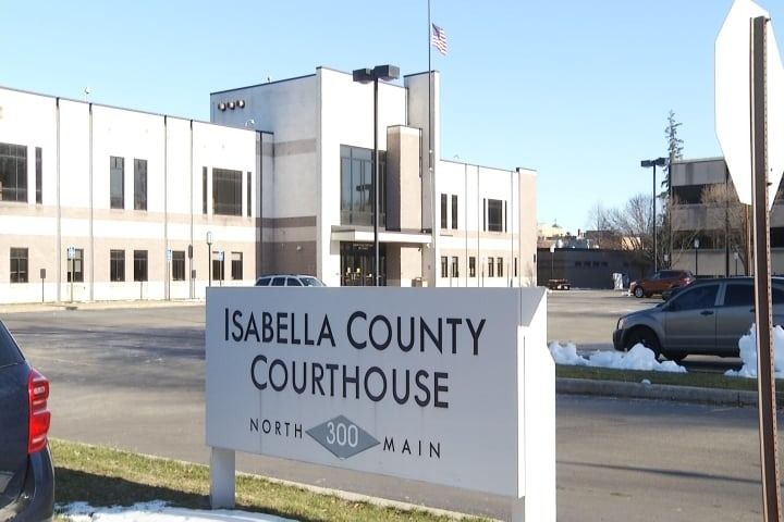 Isabella County Courthouse sign with building in the background on a sunny day.