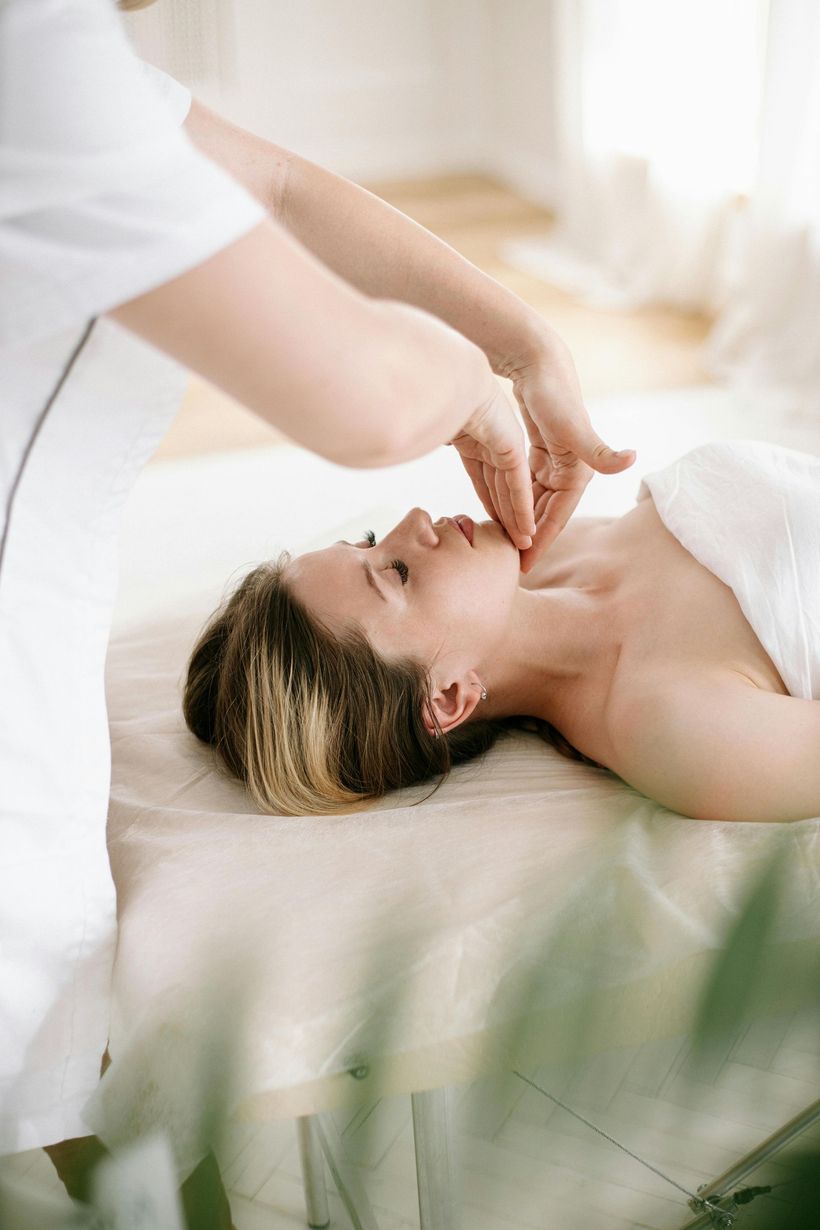 Person receiving a facial massage on a massage table.