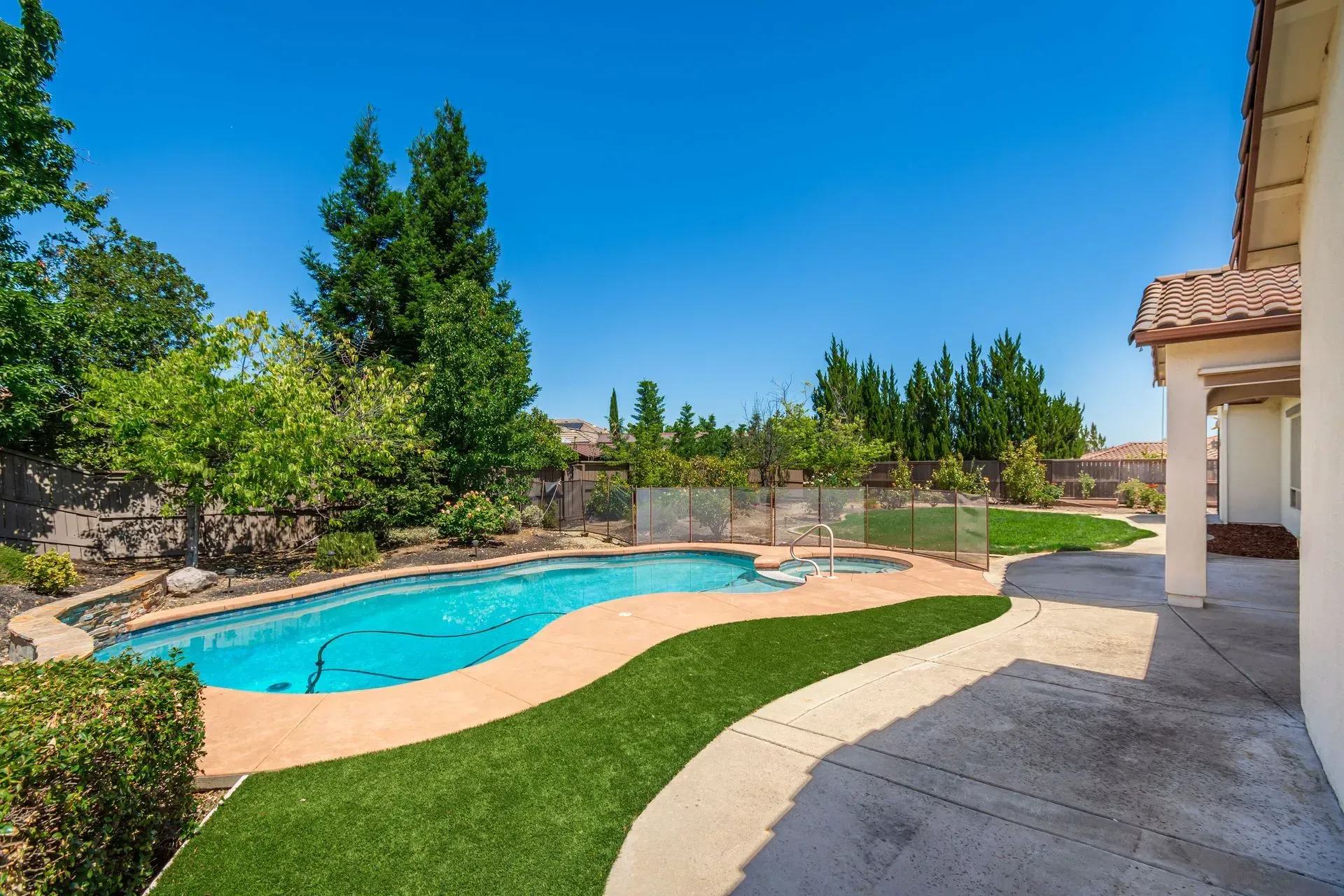 Private backyard featuring an in-ground pool and spa combo with stacked stone accents, a prime feature of this Lincoln, CA real estate listing.