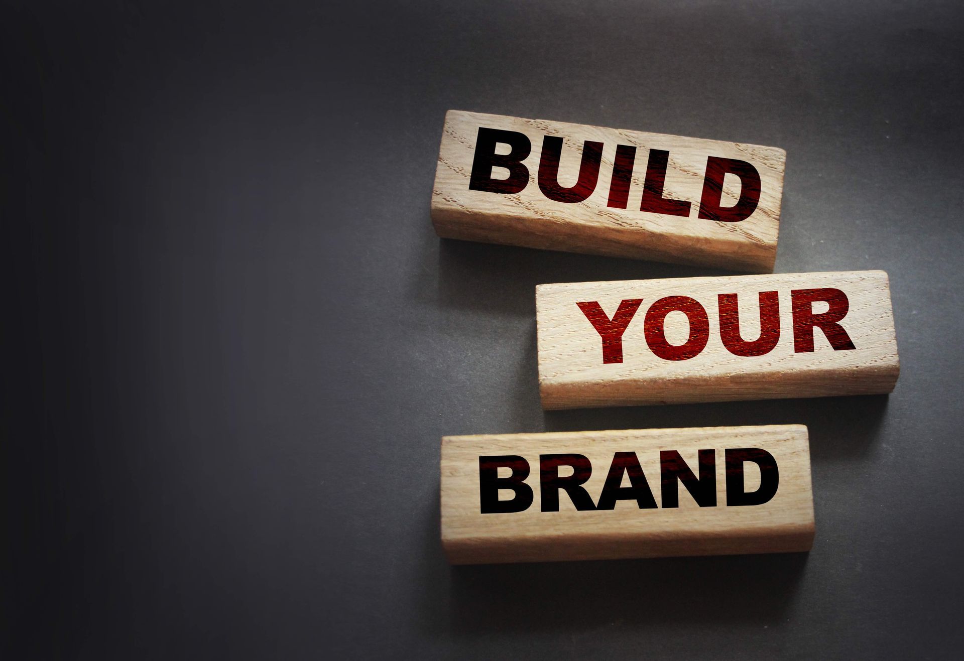 Three wooden blocks stacked against a dark background, each printed with the words