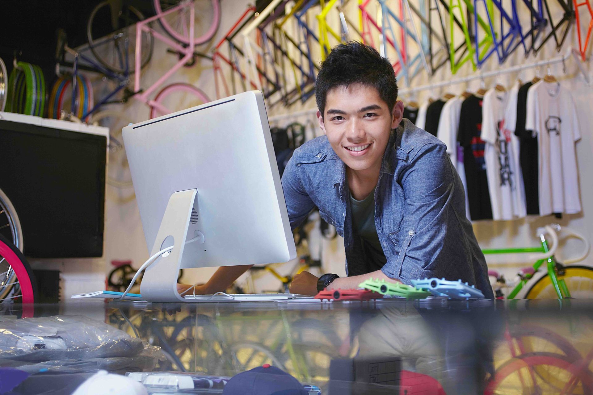 A man is standing in front of a computer in a bike store.