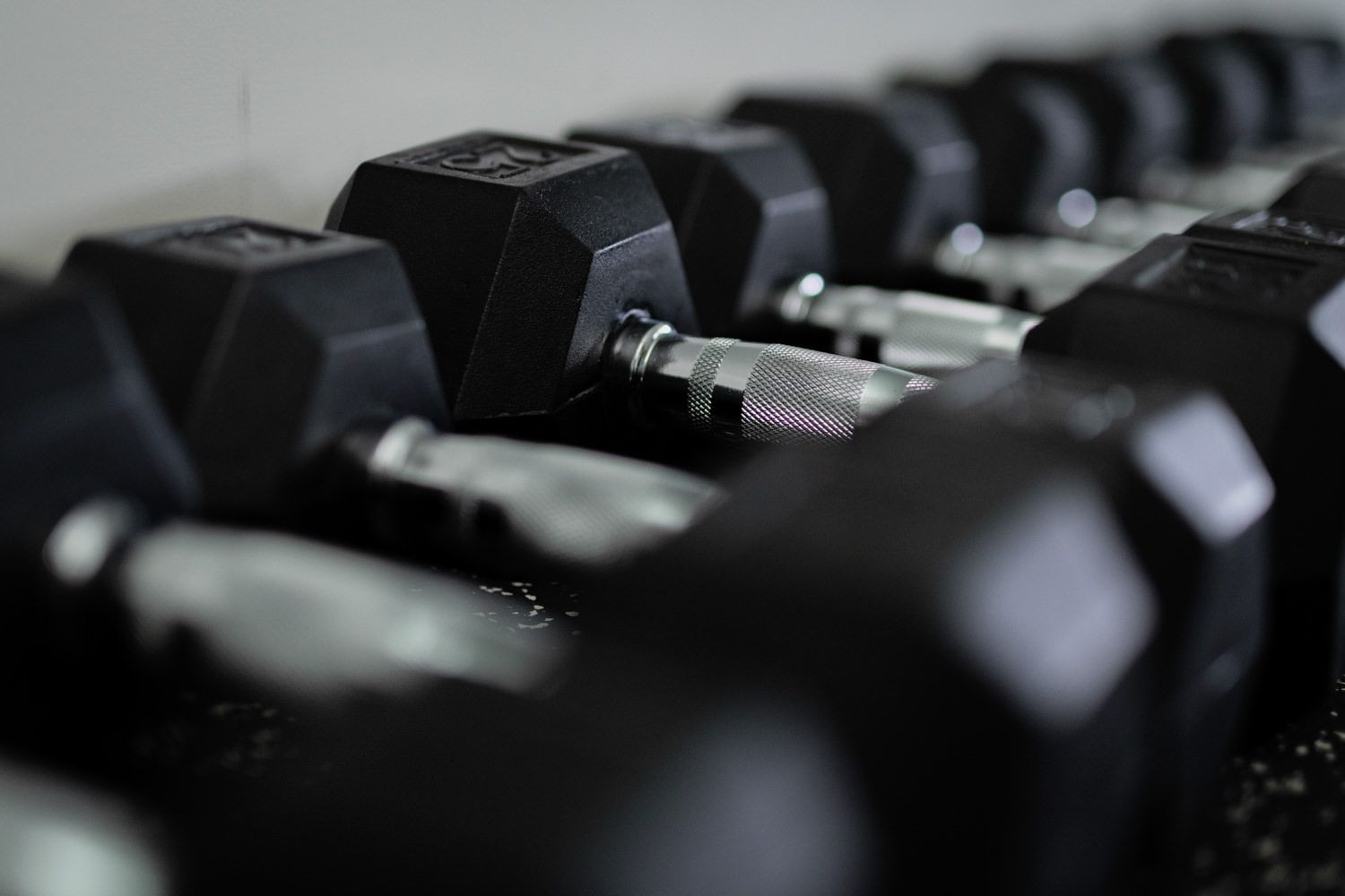 Black dumbbells lined up on a rack in a gym, ready for use.