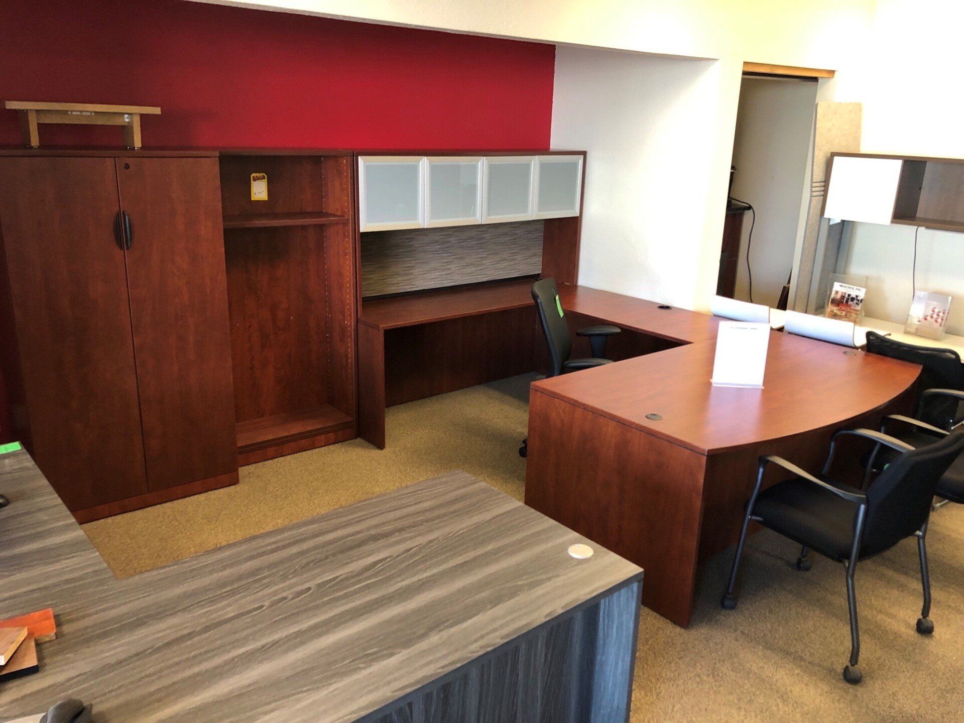 Office with U-shaped desk, cabinet, and chair; red and white walls.