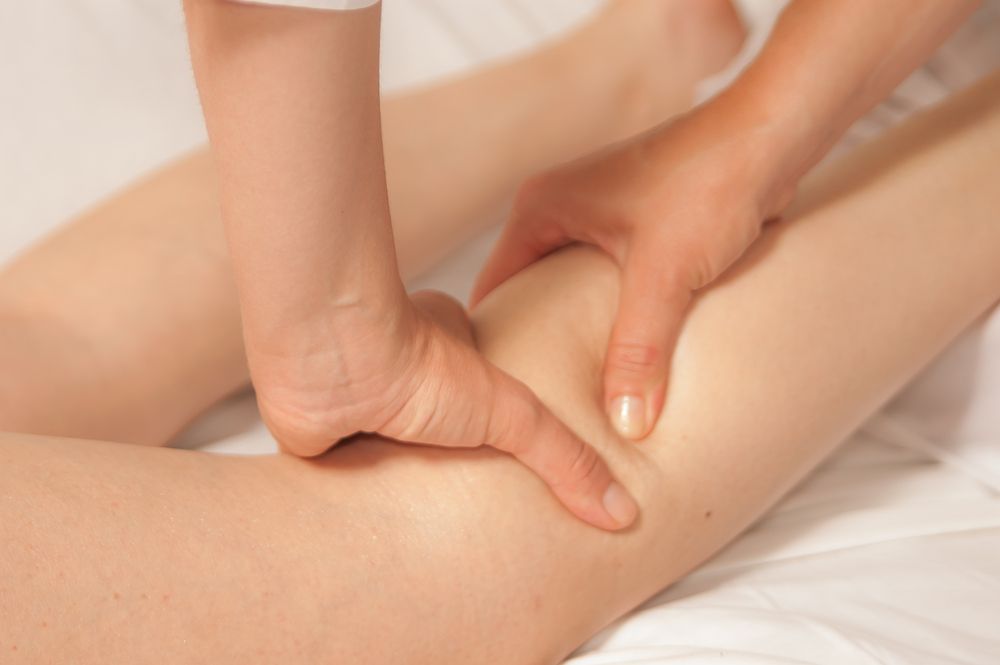 A Woman Is Massaging A Leg — Xtreme Rejuvenation Clinic, Medispa & Beauty Therapy In Maryborough, QLD