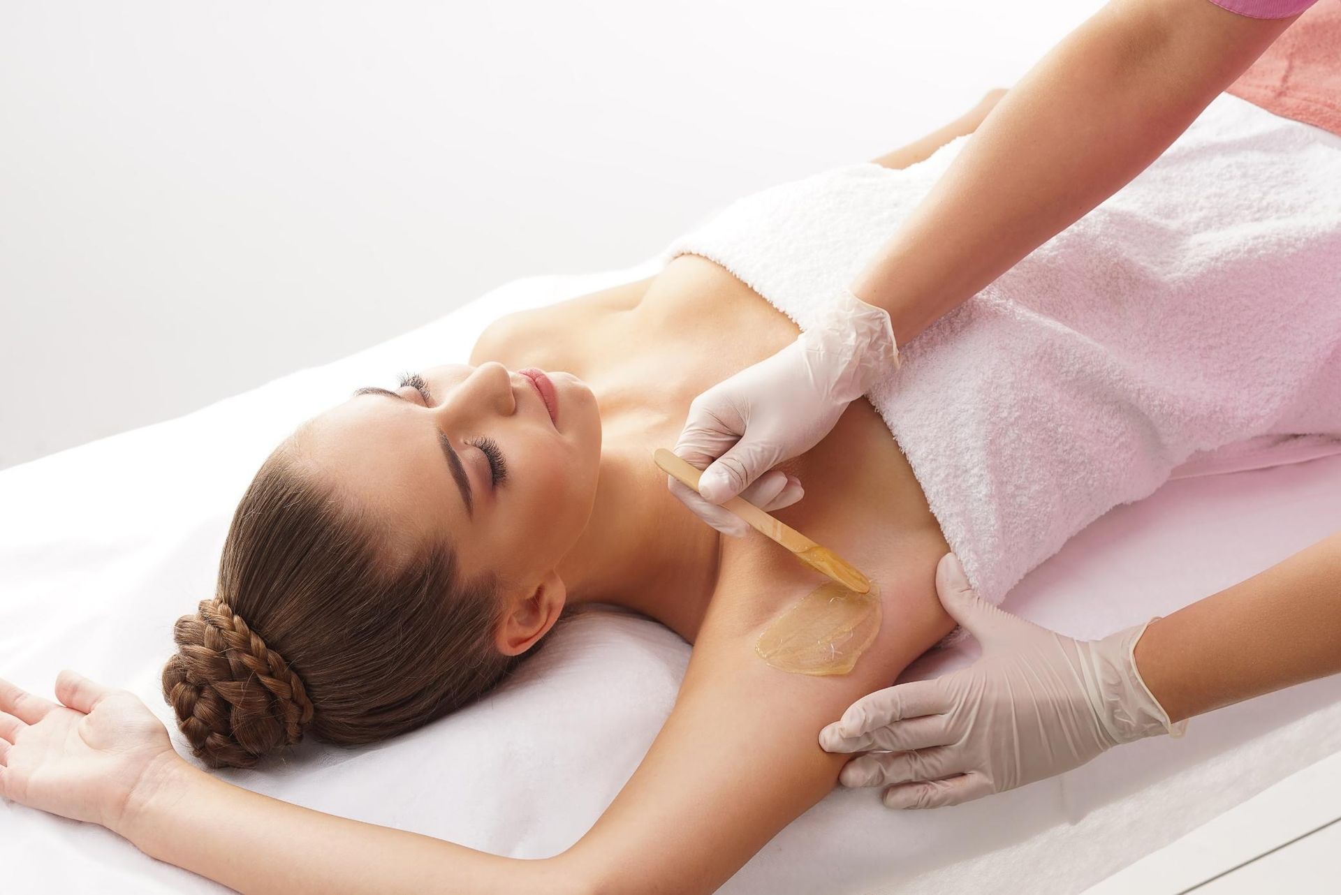 A Woman is Laying on a Bed Getting Her Armpit Waxed — Xtreme Rejuvenation Clinic, Medispa & Beauty Therapy In Maryborough, QLD