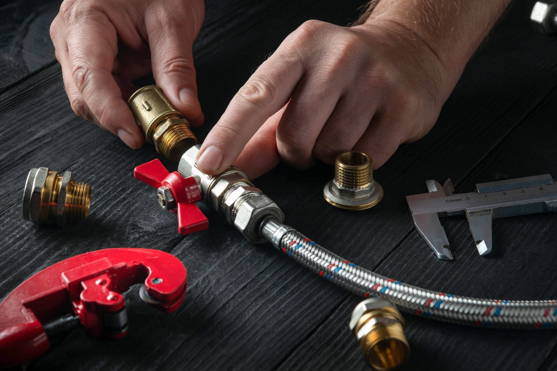 Close-up representing emergency plumbing services as plumber attaches brass fittings to hose.