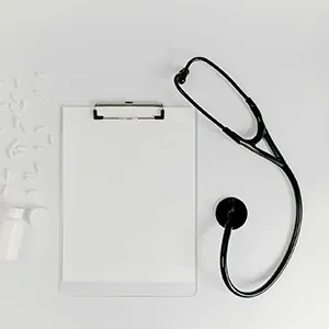 Clipboard with blank paper and a black stethoscope on a white background