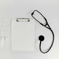 Clipboard with blank paper and a black stethoscope on a white background