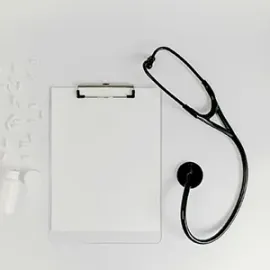 Clipboard with blank paper and a black stethoscope on a white background