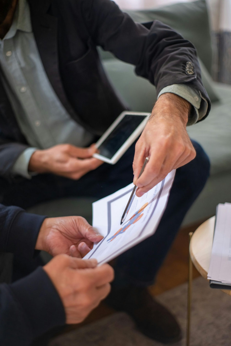 Hands exchanging printed papers and a smartphone during a business meeting