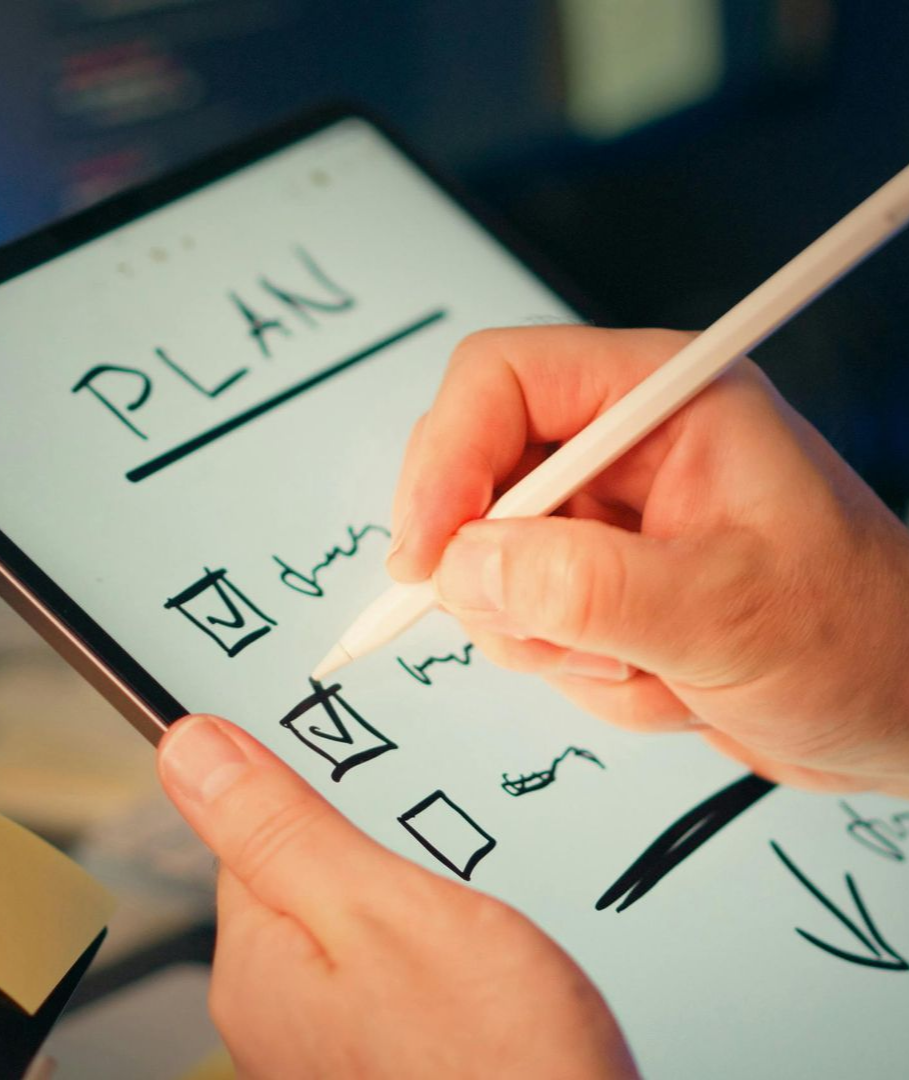 Hands checking items on a paper plan with a pen and checkbox marks.