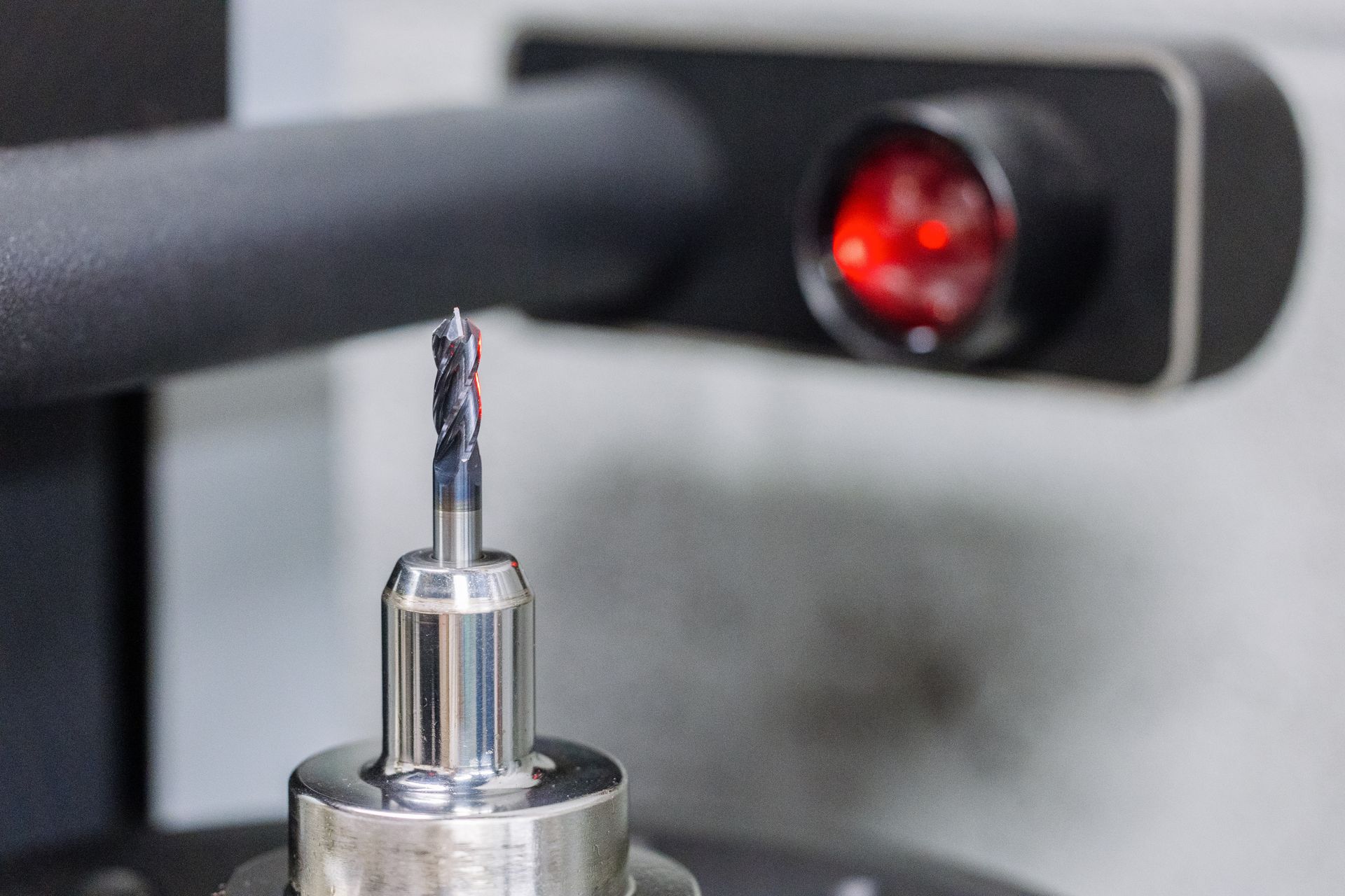 A close up of a drill bit on a machine with a red light behind it.