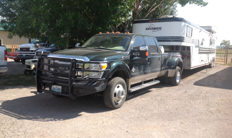 A truck with a trailer attached to it is parked on the side of the road. | Wind River Auto & Diesel
