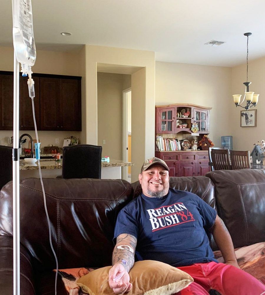 A person receiving an food poisoning iv drip treatment while relaxing on a sofa in a bright, modern living room.