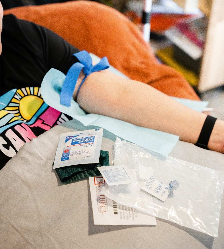 Person's arm with tourniquet, prepped for blood draw, with supplies like swabs and needle laid out.
