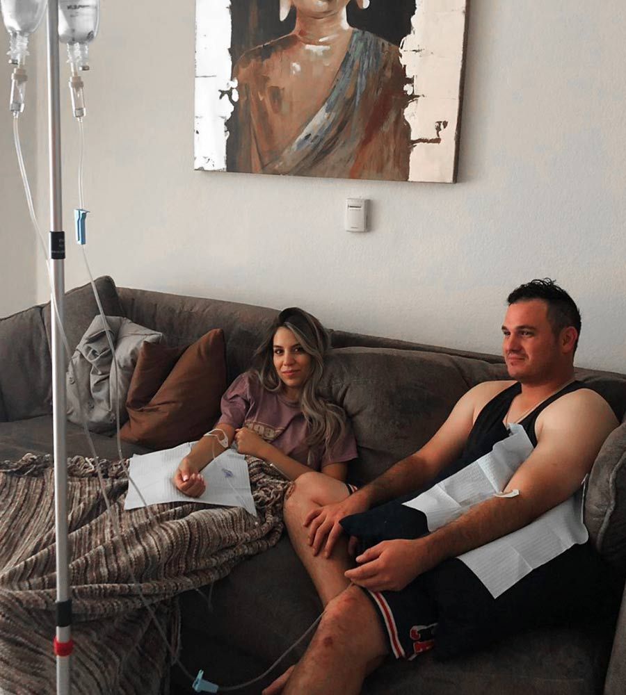Two people receiving mobile IV therapy at home while relaxing on a sofa.