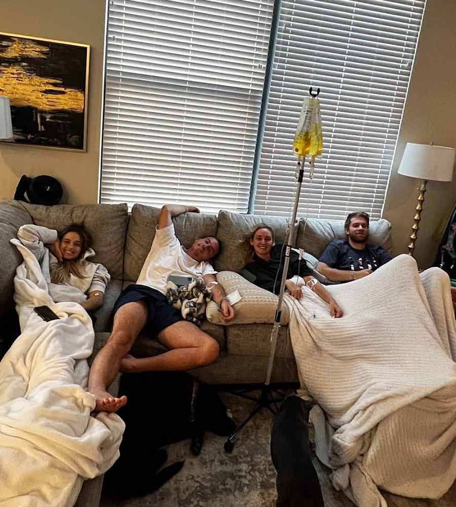 Four adults receiving group IV hydration therapy while relaxing on a couch.