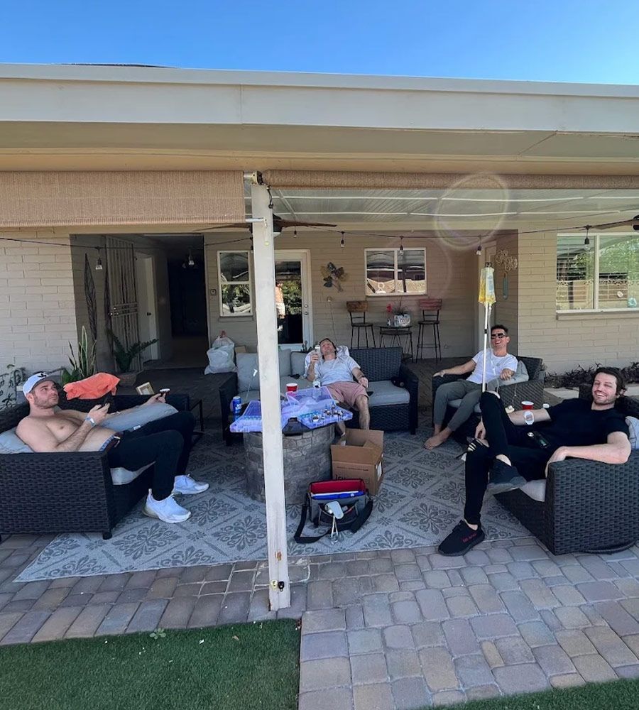 Friends relaxing on patio furniture during a group IV hydration session at home.