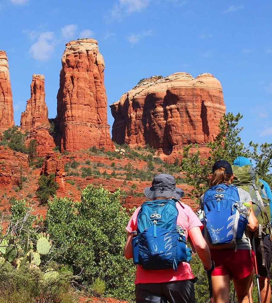 Administering mobile iv therapy for altitude sickness with Hikers wearing backpacks looking at red rock formations under a blue sky.