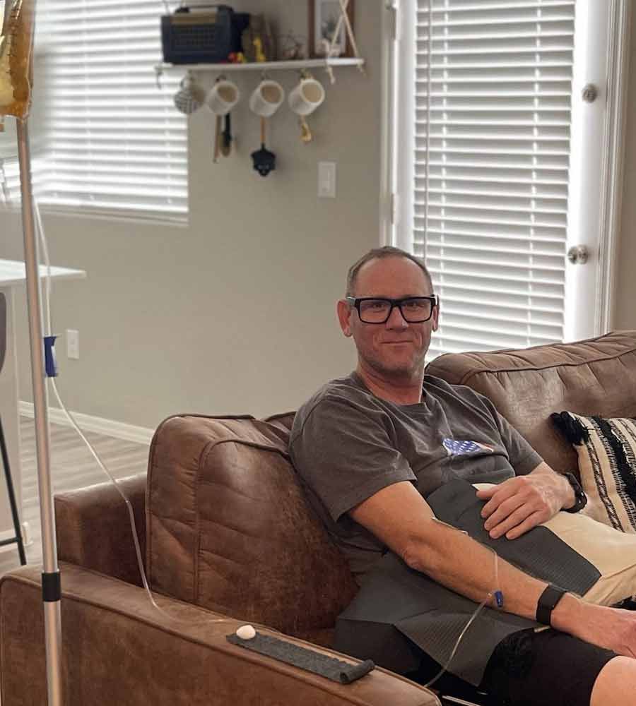 Middle-aged man relaxing on a couch during at-home IV vitamin therapy.