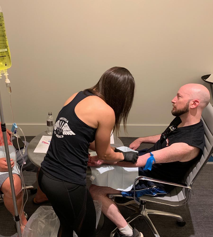 A person receiving an IV infusion, with a healthcare professional attending. Indoor setting.