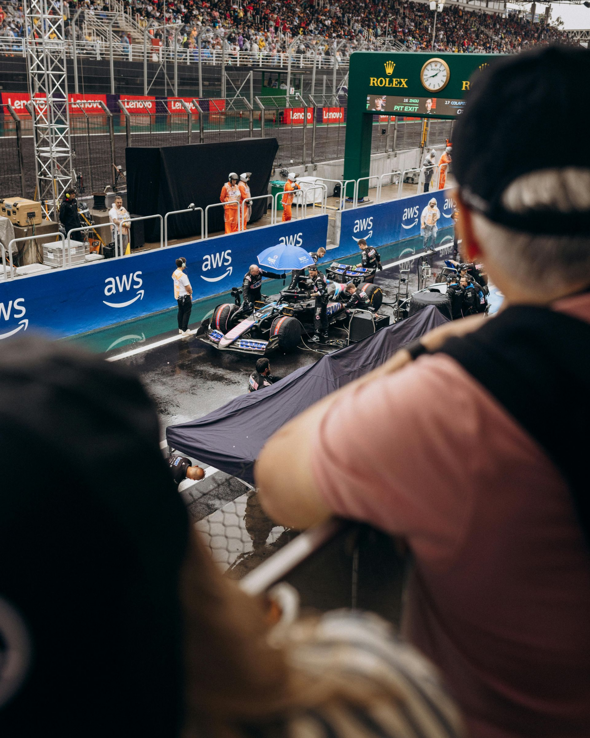 F1 race on a city track, with riders passing a grandstand and spectators watching from the stands