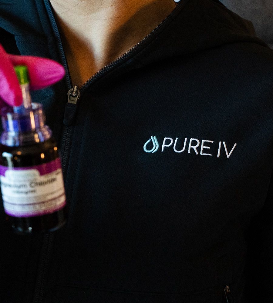 Person in black jacket holds vial with purple liquid labeled