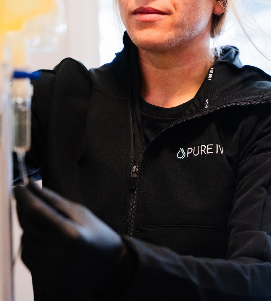 Person in black jacket and gloves holding an IV bag, likely preparing for an infusion.