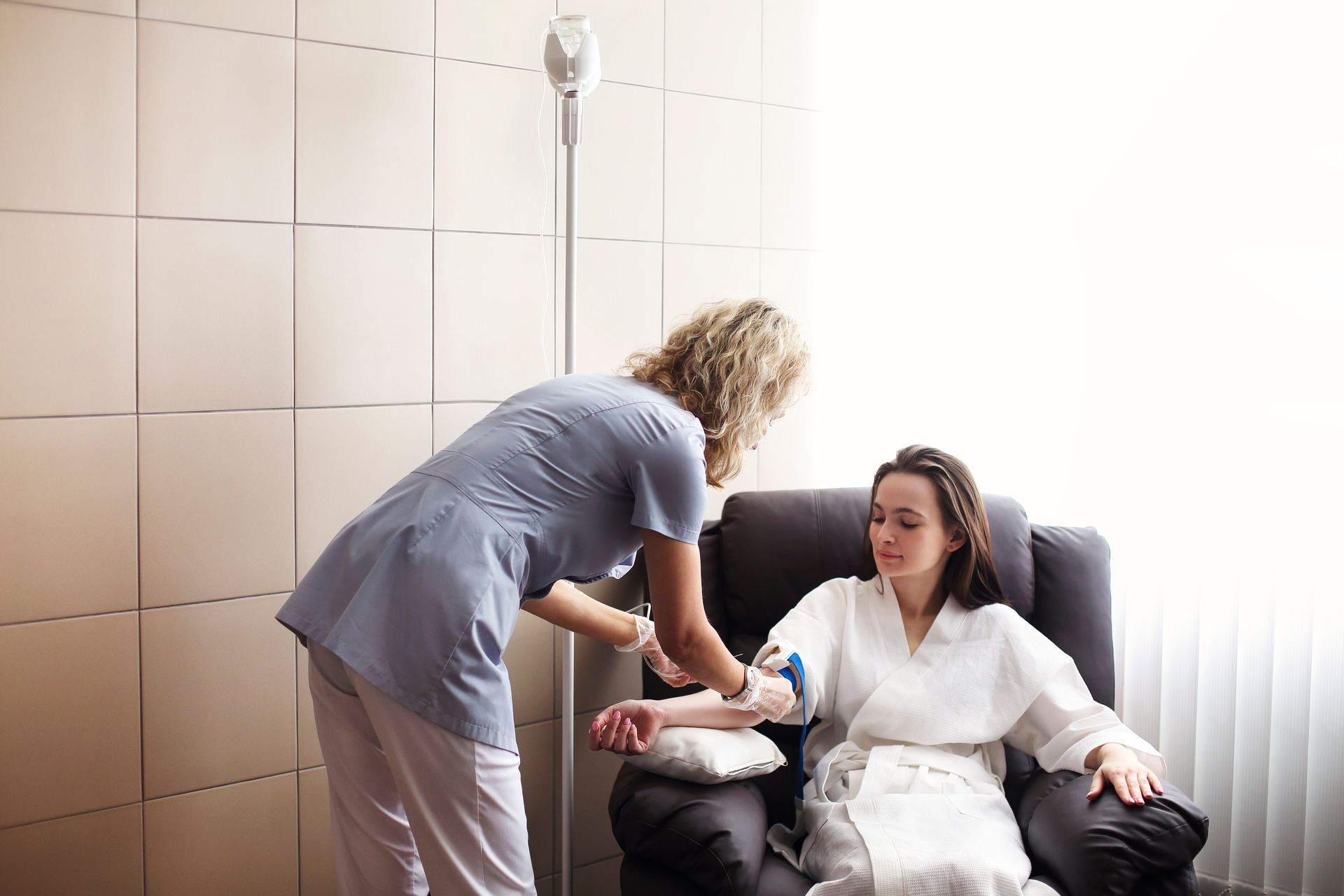 Nurse setting up IV on a patient in a recliner chair.
