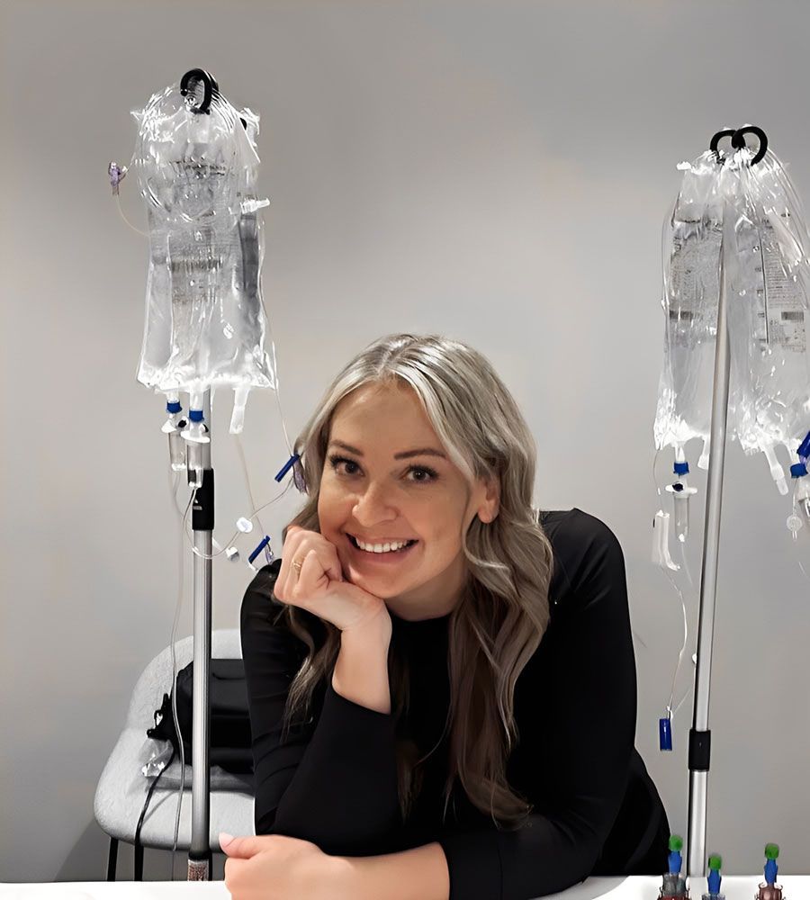 Smiling woman with IV therapy poles and hydration bags at a treatment setup.