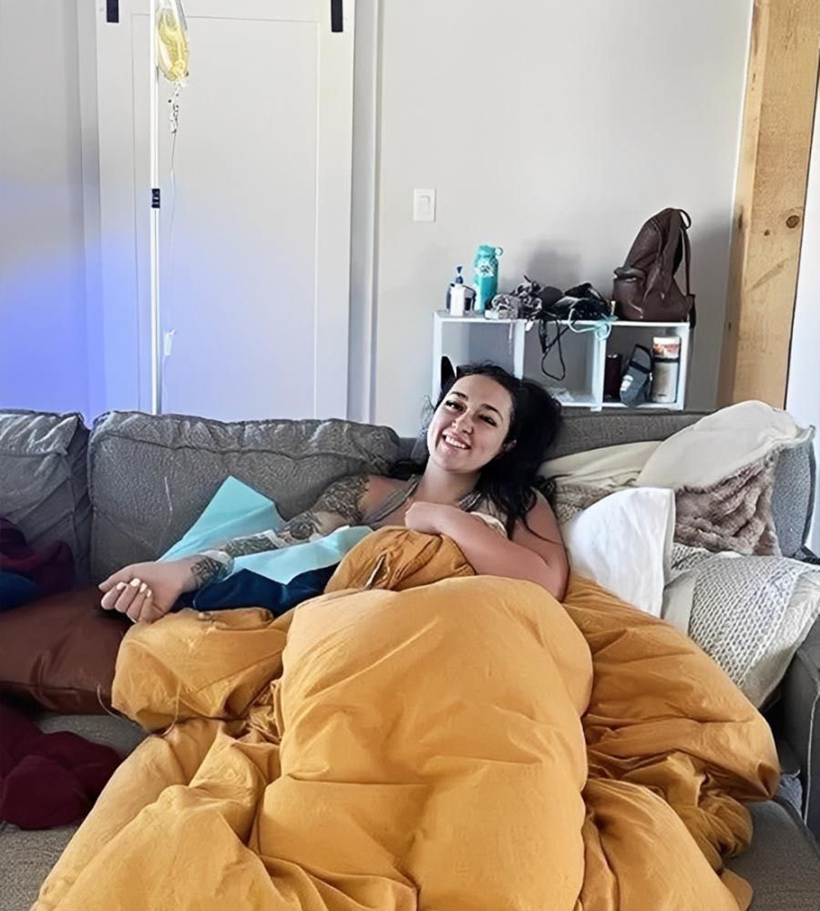 A woman looking relaxed and comfortable while receiving an iv therapy for cold and flu at home.
