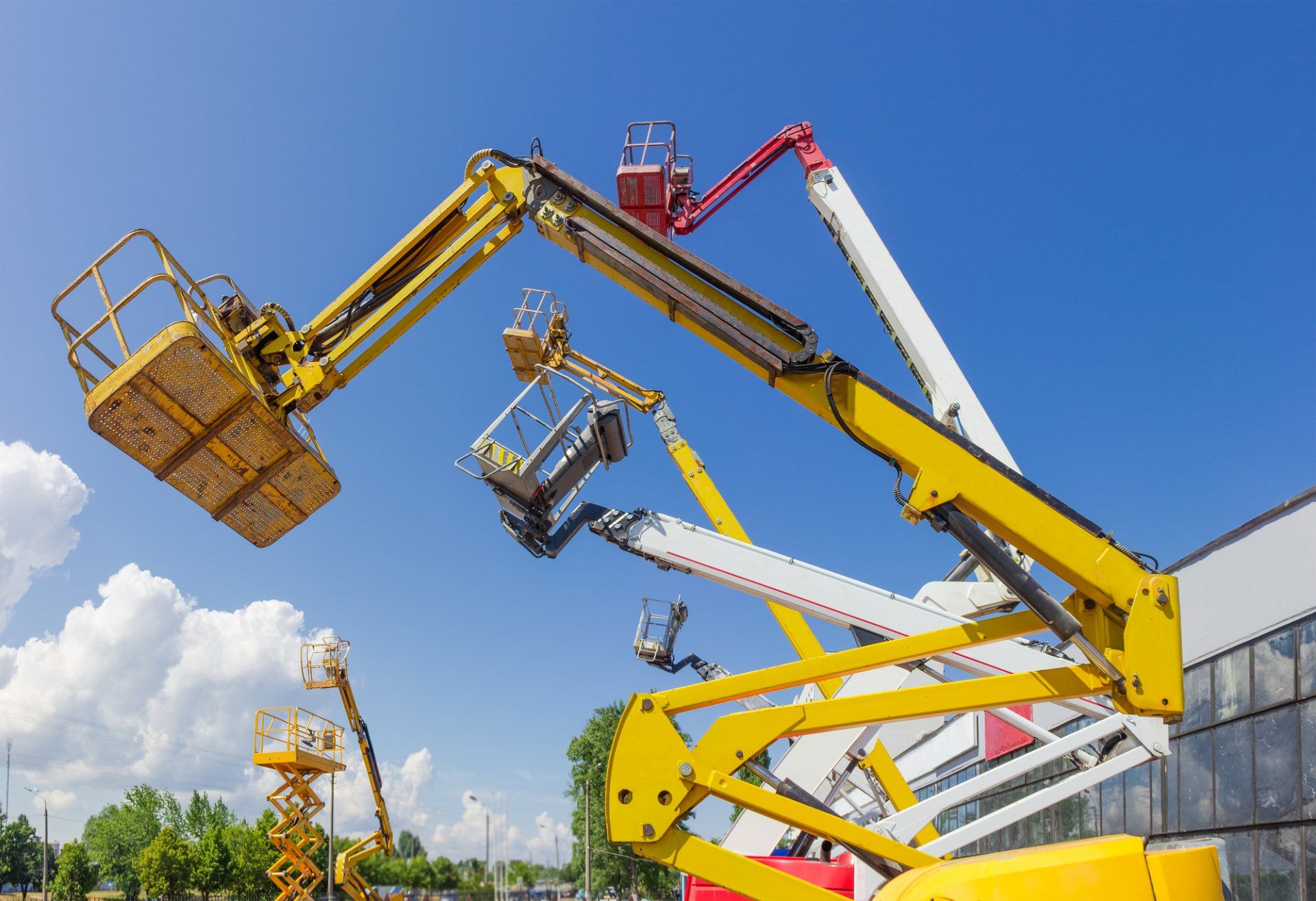 A row of aerial lifts are parked in front of a building.