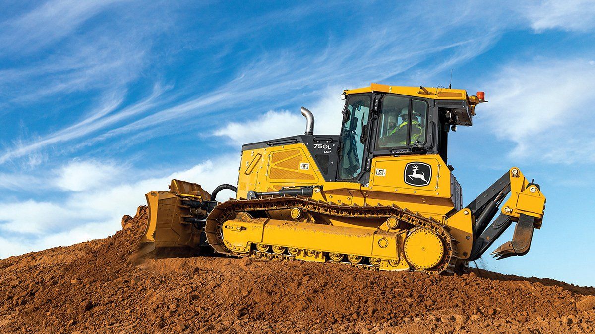 A yellow bulldozer is sitting on top of a pile of dirt.