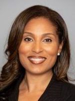 A woman in a black jacket is smiling for the camera.