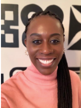 A woman wearing a pink turtleneck is smiling for the camera