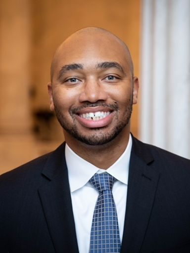 A man in a suit and tie is smiling for the camera.