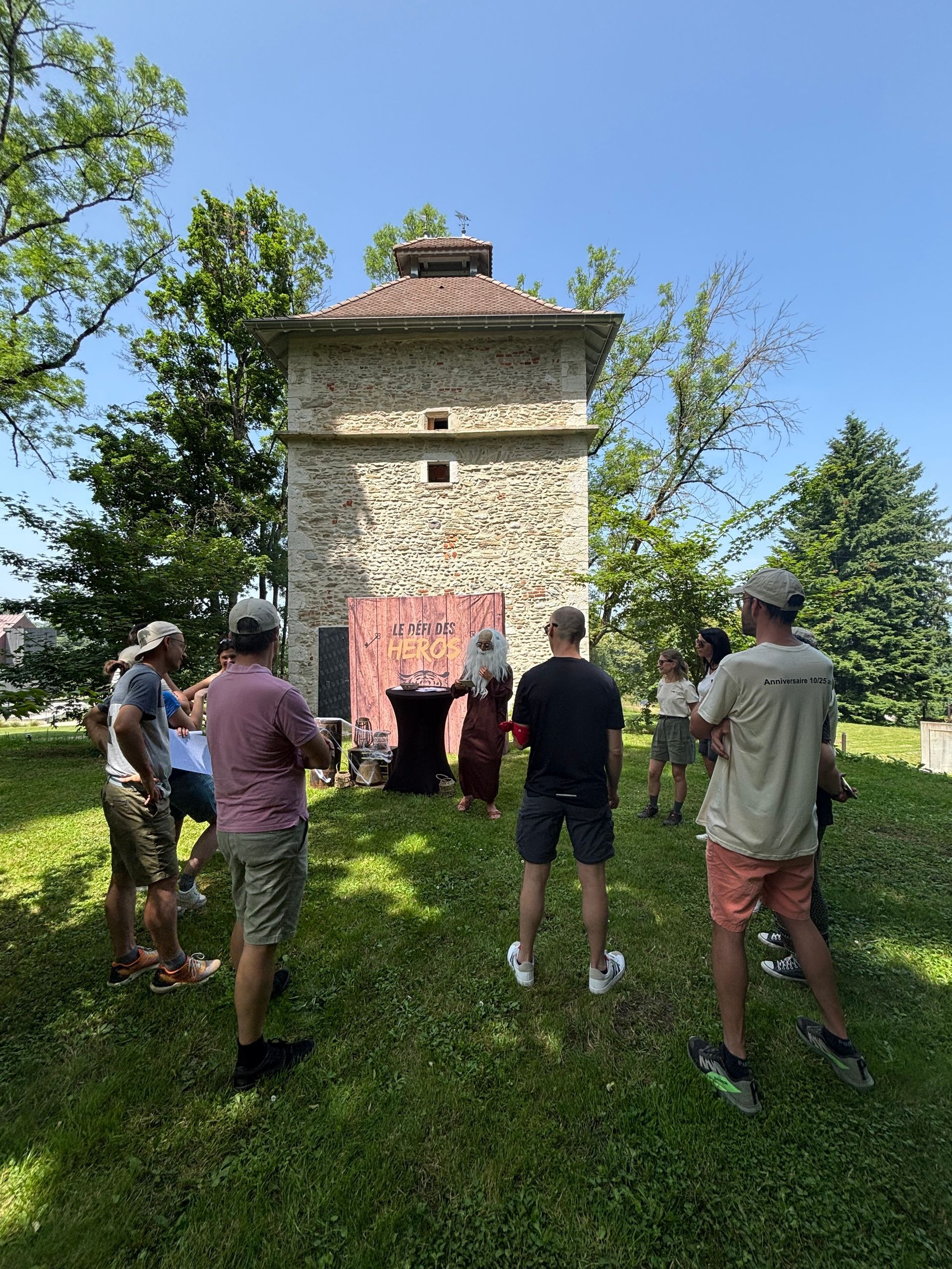 Un groupe de personnes se tient dans l'herbe devant un bâtiment en pierre.